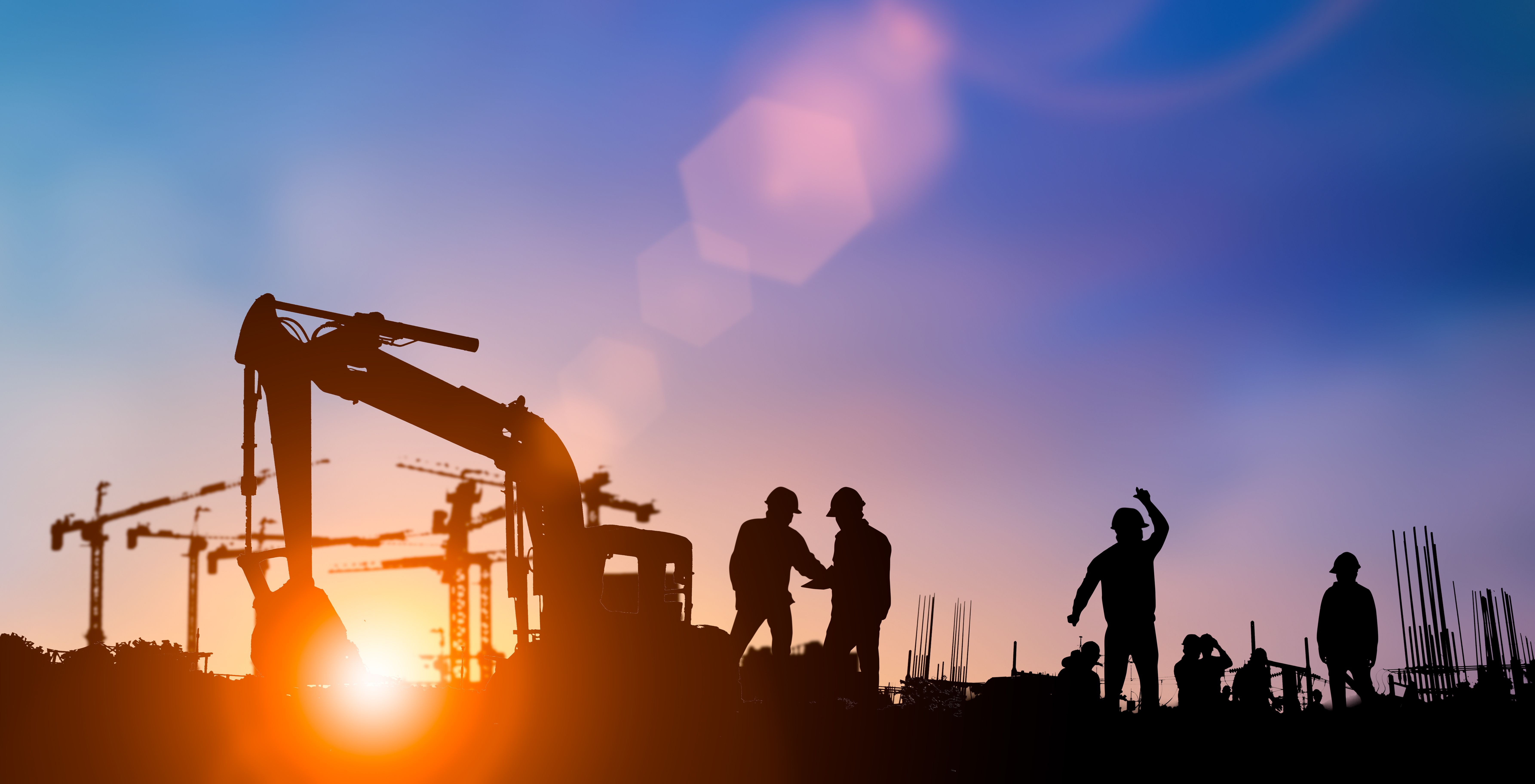 Silhouette of construction workers on site at sunrise